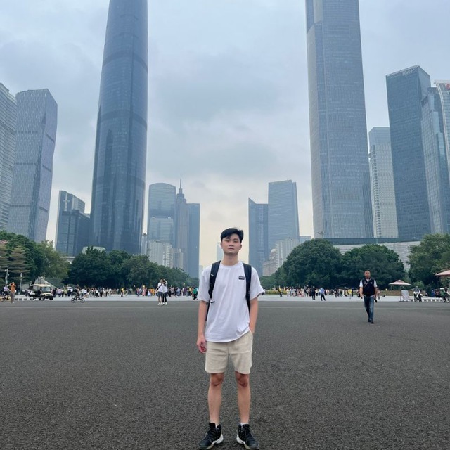Trịnh Văn Thắng standing in a city square with skyscrapers behind